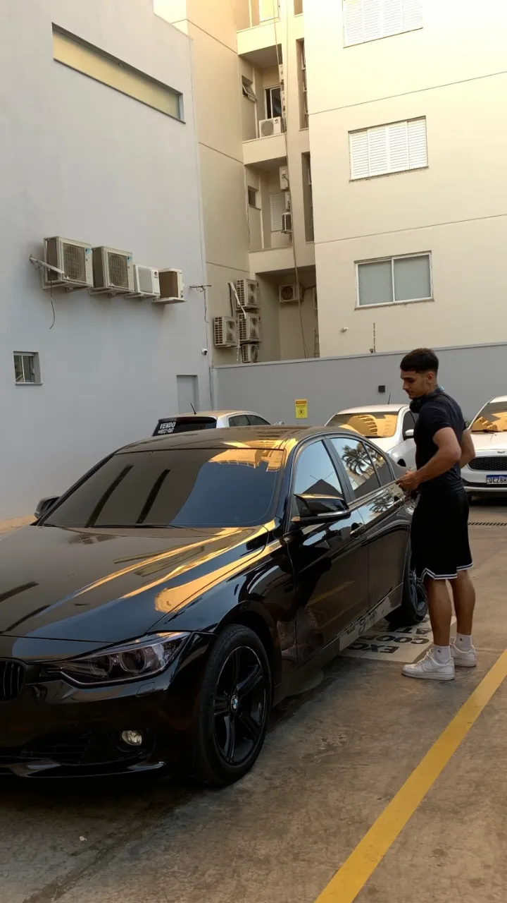Heric ao lado de um carro preto, em um estacionamento