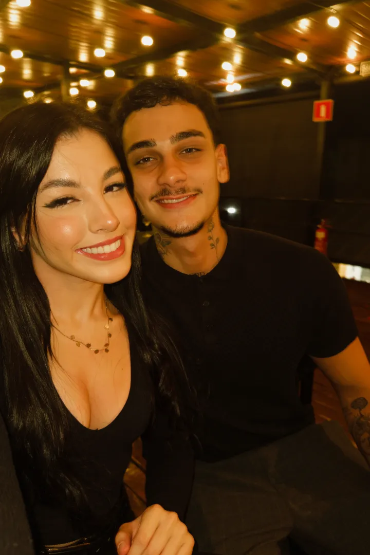 Heric sorrindo ao lado de uma amiga, em um restaurante